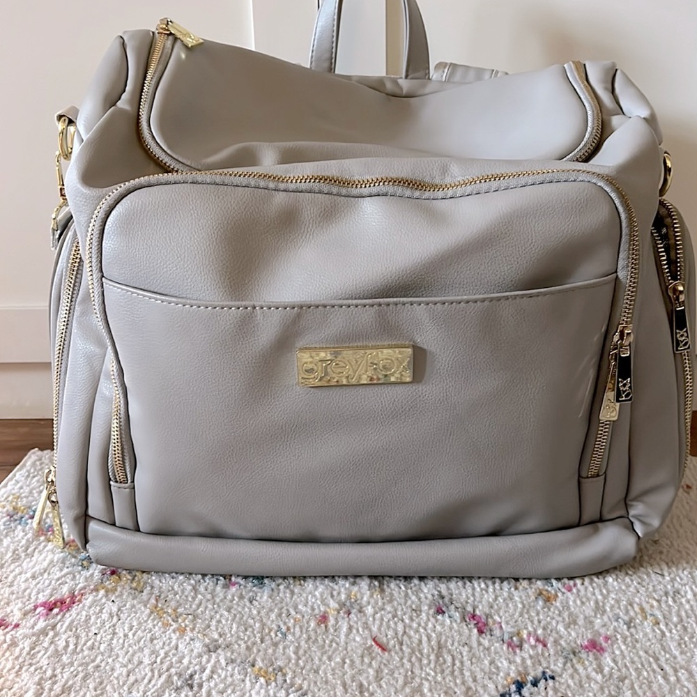 Greyfox backpack diaper bag with gold zippers; detachable shoulder strap.